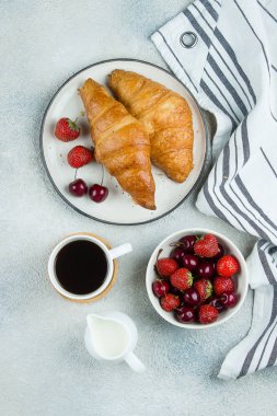 Lezzetli kahvaltı gıda konsepti. Kahve, kruvasan ve çilek açık beton arka plan üzerinde kahvaltı için. Üst görünüm, düz yatıyordu