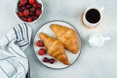 Lezzetli kahvaltı gıda konsepti. Kahve, kruvasan ve çilek açık beton arka plan üzerinde kahvaltı için. Üst görünüm, düz yatıyordu