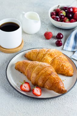 Kahve, kruvasan ve çilek açık beton arka plan üzerinde kahvaltı için. Lezzetli kahvaltı gıda konsepti. Close