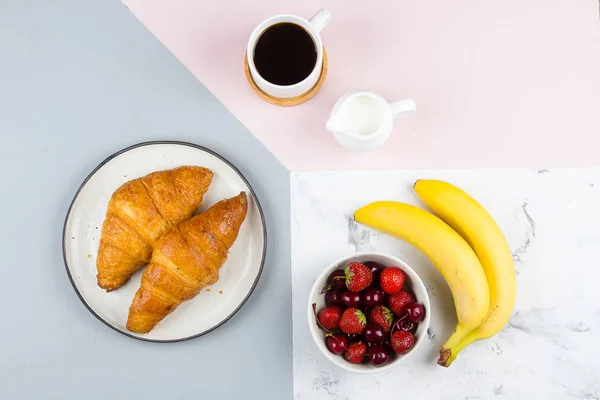 Breakfast Flat Lay with coffee, croissants and berries for breakfast on pastel tricolor background. Top view, flat lay