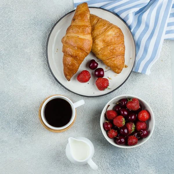 Delicioso concepto de desayuno. Café, croissants y bayas para el desayuno sobre fondo de hormigón ligero. Imagen cuadrada, vista superior — Foto de Stock