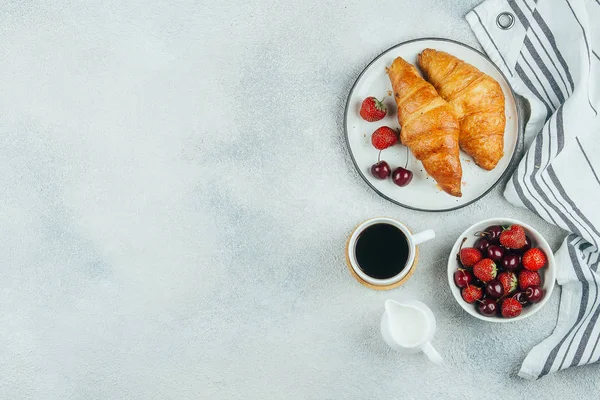 Leckeres Frühstücksbuffet Konzept. Kaffee, Croissants, Erdbeere und Kirsche zum Frühstück auf hellem Betongrund. Ansicht von oben mit Kopierraum — Stockfoto