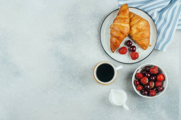 Fondo alimenticio. Café, croissants y bayas para el desayuno sobre fondo de hormigón ligero. Vista superior con espacio de copia — Foto de Stock