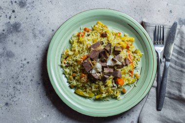 Geleneksel Asya yemekleri servis edilmektedir. Pirinç, sebze ve et gri arka planda bir plakalı Pilaf. İki bardak çay. Kopya alanı ile üst görünüm.