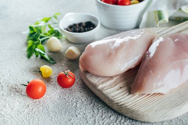 Beton masa arka planda ahşap tahta üzerinde akşam yemeği için ham tavuk göğüs Filizin ve malzemeler