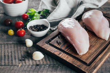 Masa arka planda ahşap tahta üzerinde akşam yemeği için ham tavuk göğsü Filizin ve malzemeler