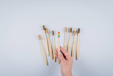 Gri arka planda bambu diş fırçaları olan düz bir kompozisyon. Çevresel bambu diş fırçaları. Sıfır atık, plastik madde konsepti. Üst görünüm, alanı kopyala