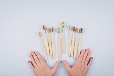 Gri arka planda bambu diş fırçaları olan düz bir kompozisyon. Çevresel bambu diş fırçaları. Sıfır atık, plastik madde konsepti. Üst görünüm, alanı kopyala