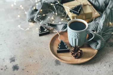 Bir kupa sıcak kahve, rahat süveter, çelenk ışıkları, hediyeler ve şenlikli dekorasyonla Noel arkaplanı. Uzayı metin için kopyala. Keyifli bir tatil kartı konsepti.