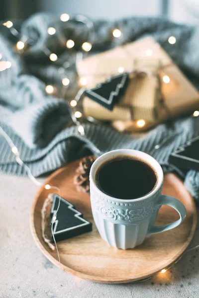 Mysig vinterkomposition med en kopp kaffe, presentförpackning, presenter, tröja och girlansljus. Jul- eller nyårskoncept 2020. Mysigt, stämning, liv, stilleben — Stockfoto