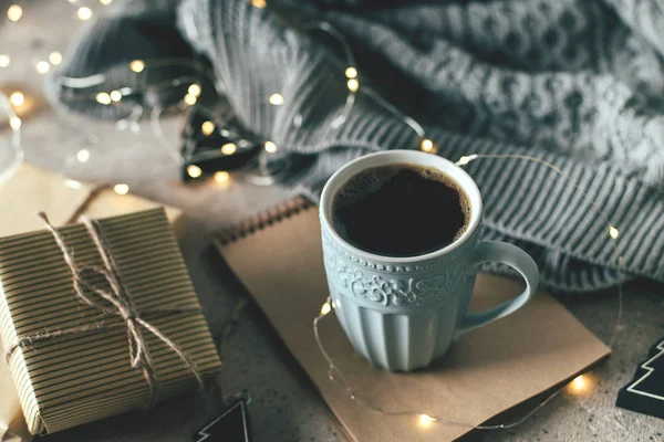 Tazza di caffè caldo, maglione accogliente, luci ghirlanda, regali e decorazioni festive. Concetto di carta di Natale accogliente umore vacanza . — Foto Stock