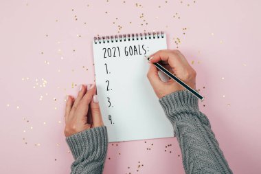Mutlu yıllar 2021. Üç renkli arka planda noel süsleriyle süslenmiş not defterine 2020 gol atan bir kadın eli. Üst manzara, düz uzanma