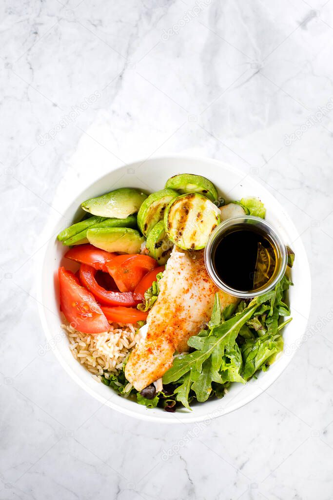 Healthy Salad Fish Bowl. Zander, vegetables, green leaves, avocado, tomato and brown rice in bowl.