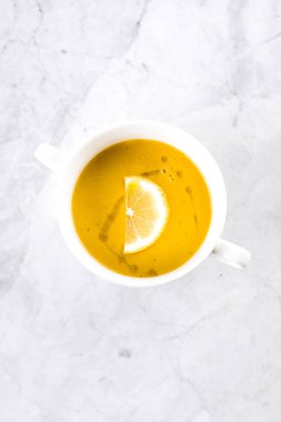 Mermer masadaki beyaz kasede mercimek çorbası. Üst görünüm.