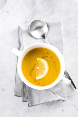 Mermer masadaki beyaz kasede mercimek çorbası. Üst görünüm.