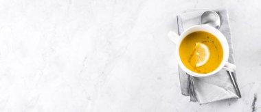 Mermer masadaki beyaz kasede mercimek çorbası. Üst görünüm.