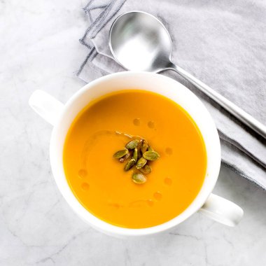 Beyaz kasede mermer masada balkabağı çorbası. Sonbahar mevsimlik çorba tabağı. Üst görünüm, alanı kopyala.