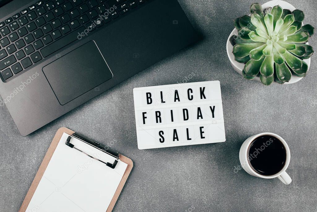 Black friday sale word on lightbox, laptop, cup of coffee, empty blank, succulent plant on grey office table. Flat lay, top view, copy space. Mockup