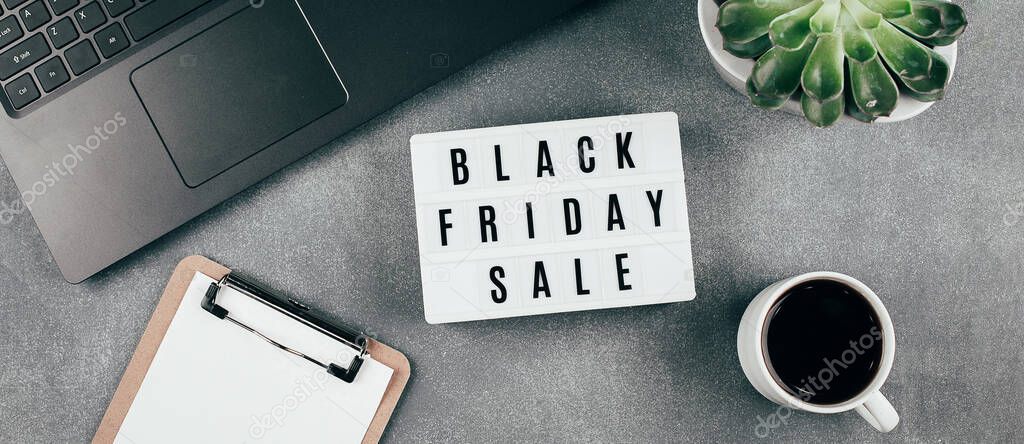 Black friday sale word on lightbox, laptop, cup of coffee, empty blank, succulent plant on grey office table. Flat lay, top view, copy space. Mockup
