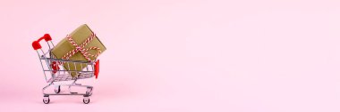 Hediye kutusuyla alışveriş arabası. Noel alışverişi, Kara Cuma satış konsepti. Fotokopi alanı ile pembe arkaplan. Web sitesi için pankart