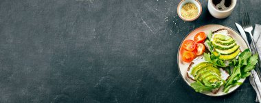 Süzme peynirli avokado tostları, roka, koyu masada bir fincan kahve. Sağlıklı kahvaltı, atıştırmalık. Üst görünüm, kopyalama alanı, pankart resmi