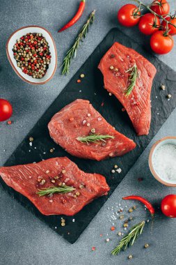 Çiğ et. Siyah tahtada çiğ biftek ve baharat. Üst görünüm