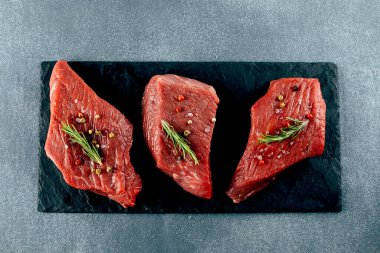 Çiğ et. Siyah tahtada çiğ biftek ve baharat. Üst görünüm