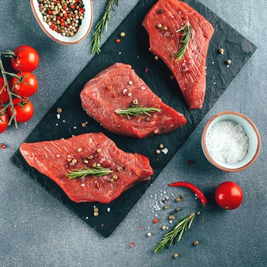 Çiğ et. Siyah tahtada çiğ biftek ve baharat. Üst görünüm