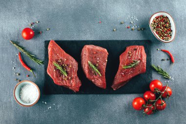 Çiğ et. Siyah tahtada çiğ biftek ve baharat. Üst görünüm