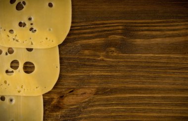 Ahşap arka plan üstten görünüm ve düz İsviçre peyniri ince dilimler yatıyordu. Doğal rustik zemin ile metin için yer