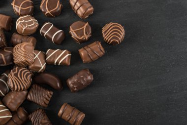 Doğal siyah taş zemin üzerine güzel yaratıcı çikolatalı tatlılar. Dağınık çikolata üstten görünüm ve düz metin için yer ile yatıyordu