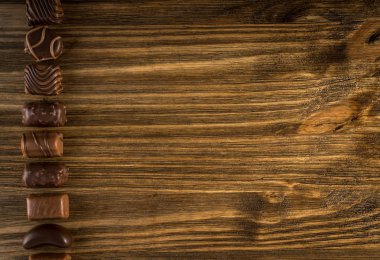 Doğal ahşap masa arka plan üzerinde güzel yaratıcı çikolatalı tatlılar. Çikolata metin için yer ile en iyi görünümü satırı