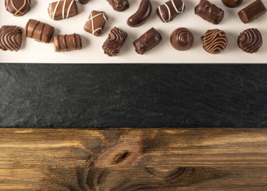 Doğal siyah taş ve ahşap zemin üzerine çikolata şeker kutusu. Mix düz Lay ve çikolata Üstten Görünüm
