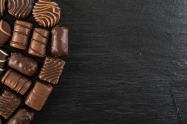 Doğal siyah taş zemin üzerine güzel yaratıcı çikolatalı tatlılar. Çikolata üstten görünüm ve düz metin için yer ile yatıyordu