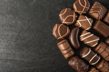 Doğal siyah taş zemin üzerine güzel yaratıcı çikolatalı tatlılar. Çikolata üstten görünüm ve düz metin için yer ile yatıyordu