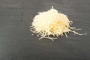 Siyah arka plan üzerine rendelenmiş peynir yığını. Yukarıdaki fotoğraf