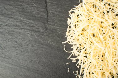 Siyah arka plan üzerine rendelenmiş peynir yığını. Yukarıdaki fotoğraf