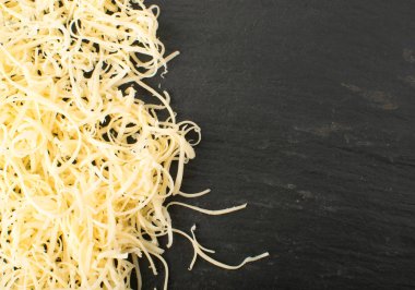 Siyah arka plan üzerine rendelenmiş peynir yığını. Yukarıdaki fotoğraf