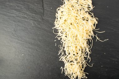 Siyah arka plan üzerine rendelenmiş peynir yığını. Yukarıdaki fotoğraf