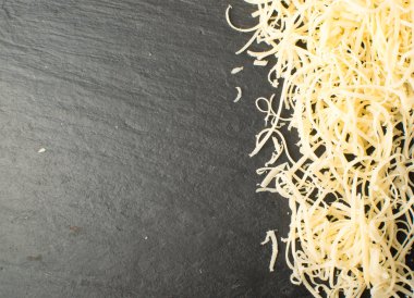 Siyah arka plan üzerine rendelenmiş peynir yığını. Yukarıdaki fotoğraf