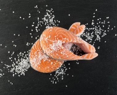 Doğal siyah arka plan üzerine çiğ somon Steak dilim. Kalın parça taze kırmızı balık ya da tuz ve baharatlar ile alabalık