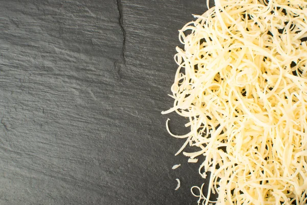 Siyah arka plan üzerine rendelenmiş peynir yığını. Yukarıdaki fotoğraf