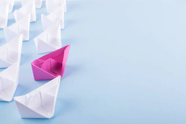 One Unique Pink Paper Boat among Many Ones. Different Paper Ships as Individuality and Leadership Concept