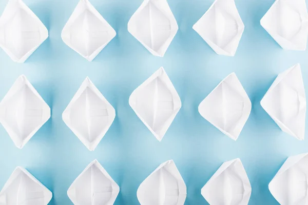 White Paper Boats or Paper Ships Origami on Blue Background Top View
