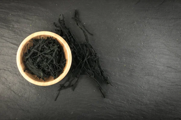 Heap of Dry Wakame Seaweed on Black Stone Background. Healthy Algae Food with Place for Text