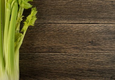 Ham yeşil kereviz ahşap arka plan üstten görünüm üzerinde takip ediyor. Eski ahşap rustik masa metin veya boşaltmak için yer ile taze organik sebze