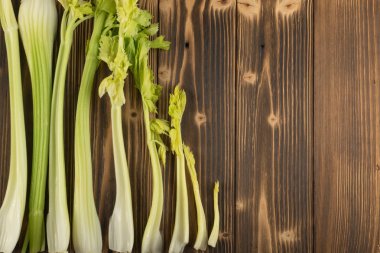 Ham yeşil kereviz koleksiyonu ahşap arka plan üstten görünüm üzerinde takip ediyor. Eski ahşap rustik masa üzerinde taze organik sebze kümesi