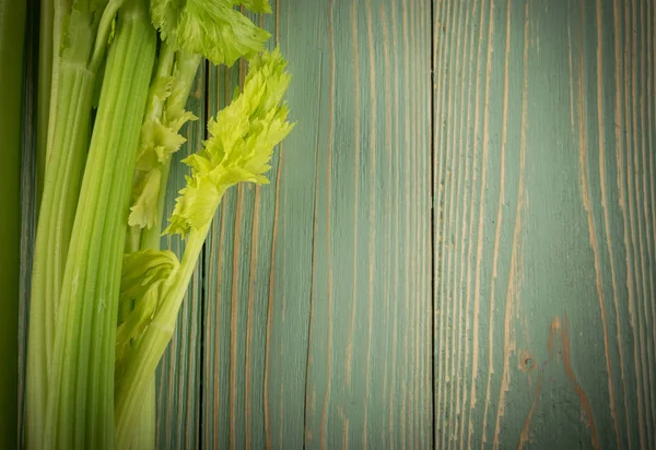 Ham yeşil kereviz ahşap arka plan üstten görünüm üzerinde takip ediyor. Eski ahşap rustik masa metin veya boşaltmak için yer ile taze organik sebze