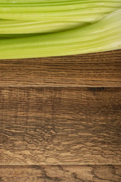 Ham yeşil kereviz ahşap arka plan üstten görünüm üzerinde takip ediyor. Eski ahşap rustik masa metin veya boşaltmak için yer ile taze organik sebze
