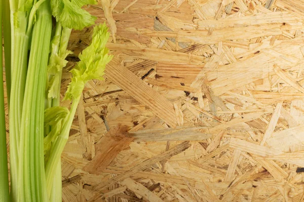 Ham yeşil kereviz ahşap arka plan üstten görünüm üzerinde takip ediyor. Eski ahşap rustik masa metin veya boşaltmak için yer ile taze organik sebze
